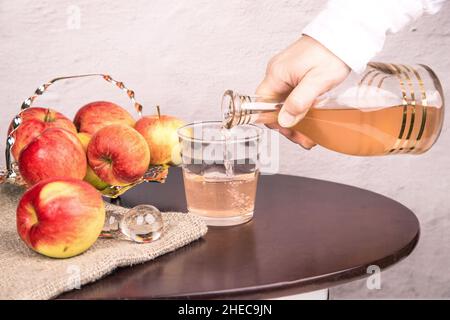 La main d'une femme verse le vinaigre de cidre de pomme dans des verres.Le concept de contrôle du poids Banque D'Images