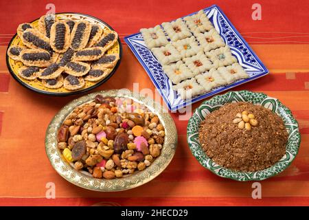 Plats traditionnels marocains avec Ashura, biscuits au chocolat et sellou sur une table Banque D'Images