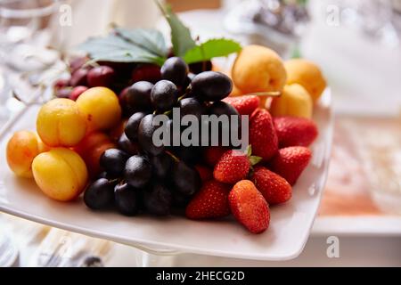 Fruits sur une assiette dans un restaurant.Fraises, raisins noirs, abricots Banque D'Images