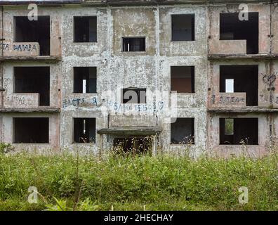 Façade d'une maison abandonnée de 3 étages avec arbres en pleine croissance juste au-dessus du bâtiment. Banque D'Images