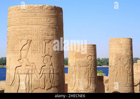 Égypte, haute Égypte, vallée du Nil, Kom Ombo, temple de Sobek et Haroeris, cour, première colonne avec hiéroglyphes et bas-relief représentant Horus (à gauche) et Nephthys (à droite) avec le Nil en arrière-plan Banque D'Images