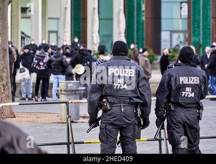 Braunschweig, Allemagne, 8 janvier 2022 : vue arrière des officiers de police noirs en uniforme à une barrière séparant les parties contestantes lors d'une manifestation Banque D'Images