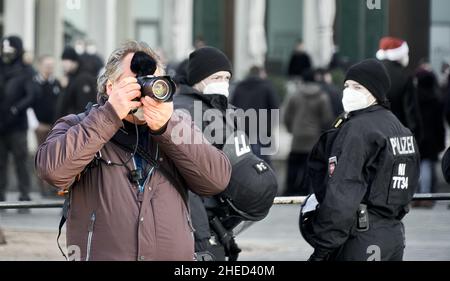 Braunschweig, Allemagne, 8 janvier 2022: Journaliste avec caméra avec des policiers derrière lui prenant des photos à une manifestation, foyer sélectif Banque D'Images