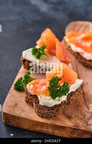 Mini sandwiches avec du saumon, du fromage caillé, du persil et du pain de seigle sous forme de coeurs.Saint-Valentin cuisine créative maison.J'adore le design du petit déjeuner.Séle Banque D'Images