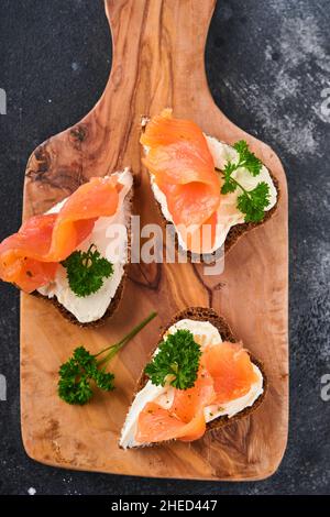 Mini sandwiches avec du saumon, du fromage caillé, du persil et du pain de seigle sous forme de coeurs.Saint-Valentin cuisine créative maison.J'adore le design du petit déjeuner.Séle Banque D'Images