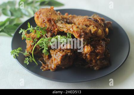 Rôti de poulet sec de style Kerala.Poulet cuit dans une sauce épicée de tomates oignons et d'épices servi avec des morceaux de cuisses de poulet sur le dessus.Prise de vue sur fond blanc Banque D'Images