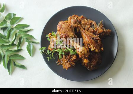 Rôti de poulet sec de style Kerala.Poulet cuit dans une sauce épicée de tomates oignons et d'épices servi avec des morceaux de cuisses de poulet sur le dessus.Prise de vue sur fond blanc Banque D'Images