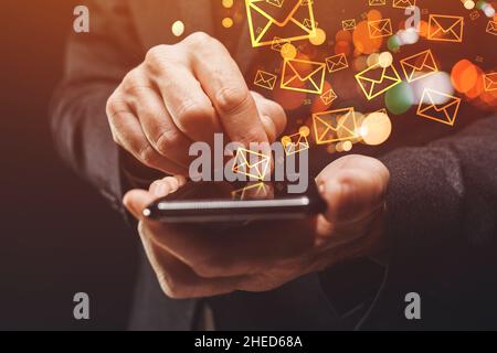 Messagerie groupée, homme d'affaires envoyant une grande quantité de SMS sur smartphone, gros plan des mains avec une attention sélective Banque D'Images