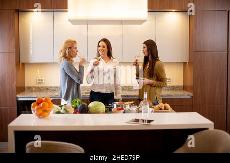 Groupe de jolies jeunes femmes préparant un repas, buvant du vin blanc et ayant un bon moment Banque D'Images