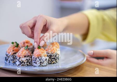 Gros plan des sushis sur l'assiette et des femmes qui mettent la garniture Banque D'Images