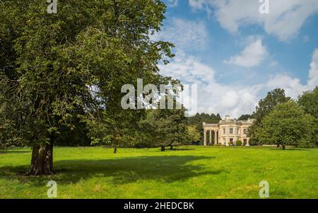 Herbe verte luxuriante flanquée d'arbres au-dessus du ciel bleu nuageux et vue sur le majestueux Centre bouddhiste dans la campagne rurale de Percy Kilnwick, Royaume-Uni. Banque D'Images