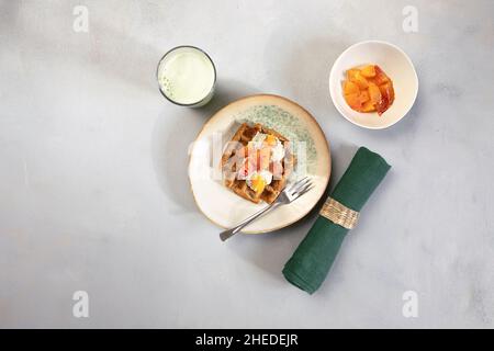 Gaufres végétaliennes sans gluten avec pudding, oranges et lait vert sur fond neutre.Repas santé, délicieux petit déjeuner maison. Banque D'Images