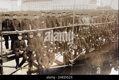 Un groupe de soldats allemands de la première Guerre mondiale s'est réuni sur un pont en bois de fortune le long du Rhin ou de l'un de ses affluents.En arrière-plan, il y a un wearhouse pour Rhein und See Speditionsgesellschaft mbH et Mannheimer Lagerhaus-Gesellschaft. Banque D'Images