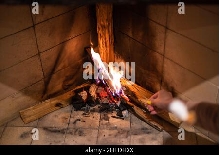 Guimauves sur bâton rôtisent sur feu de camp sur fond noir.Les gens prennent des guimauves autour de la cheminée, appréciant leurs vacances.Mains d'amis rôtisant des guimauves au feu dans le gril en gros plan Banque D'Images