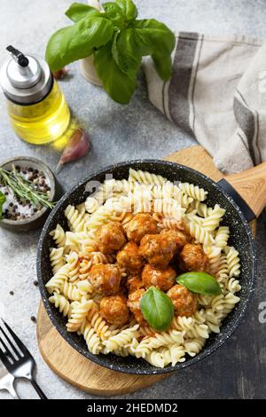 Cuisine italienne.Pâtes italiennes fusilli avec boulettes de viande sauce tomate et basilic sur fond de pierre grise. Banque D'Images
