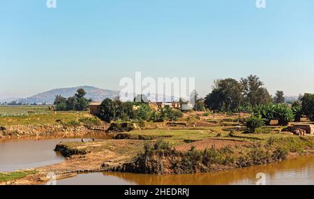 Antananarivo, Madagascar - 07 mai 2019: Personnes travaillant près de la rivière sur des maisons de jour ensoleillées à la colline en arrière-plan Banque D'Images