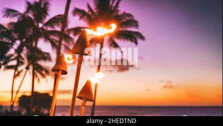 Fête sur la plage au luau d'Hawaï au coucher du soleil.Des torches tiki hawaïennes illuminées d'un feu dans le restaurant de l'hôtel de luxe.Bannière panoramique de l'aloha hawaïen Banque D'Images
