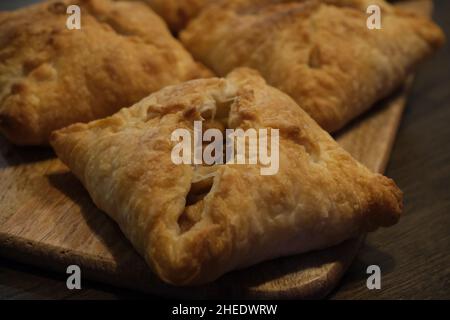 Poches de pommes maison fraîches avec croûte dorée sur une planche de service en bois Banque D'Images