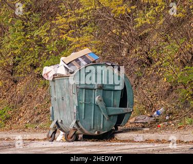 Ouvrir un conteneur métallique rempli de déchets de plastique et de papier sur la route rurale à l'extérieur Banque D'Images