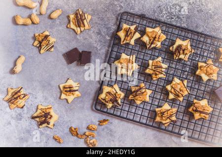 Biscuits faits maison en forme d'étoile avec garniture caramel aux noix et chocolat, sur un panier rafraîchissant et fond gris, vue du dessus Banque D'Images