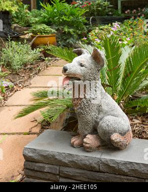 Grand jardin en béton ornement, statue d'un chien heureux, un chiot de bétail heureux, avec la bouche ouverte et la langue pendante, dans un jardin Banque D'Images