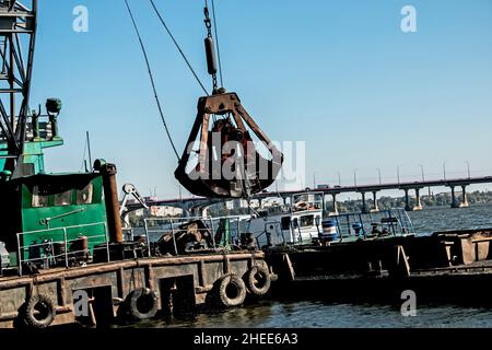 Nettoyage de l'île nouvellement formée des déchets industriels sur le Dniepr avec une drague.Le godet décharge la boue sur la barge.Concept d'écologie. Banque D'Images