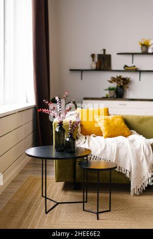 Un canapé vert avec des oreillers jaunes et un double noir Table basse et couverture dans une vie moderne de style scandinave intérieur de la chambre Banque D'Images