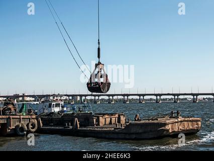 Nettoyage de l'île nouvellement formée des déchets industriels sur le Dniepr avec une drague.Le godet décharge la boue sur la barge.Concept d'écologie. Banque D'Images