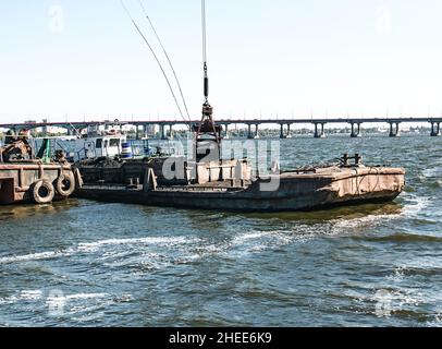 Nettoyage de l'île nouvellement formée des déchets industriels sur le Dniepr avec une drague.Le godet décharge la boue sur la barge.Concept d'écologie. Banque D'Images