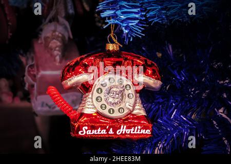 Santas Hotline rouge rétro téléphone ornement suspendu sur l'arbre de Noël bleu - gros plan et paillettes sur fond sombre flou - pièce pour copie Banque D'Images