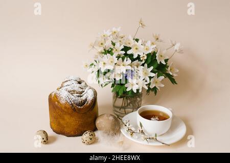 Gâteau de Pâques à l'intérieur. Faites de la spécialité avec des raisins secs, des fruits confits et une saupoudré de sucre. Gâteau fait maison. Oeufs, une tasse de thé et fleurs de printemps dans un v Banque D'Images