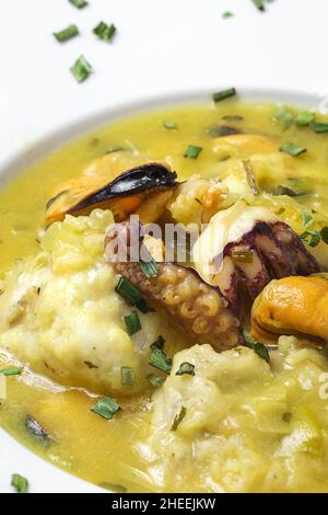 Gros plan du plat de cuisine typique du pays Basque de lotte avec calmar, crevettes et moules dans la sauce verte garni de persil Banque D'Images