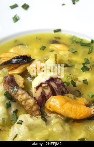 Vue de dessus de plat de gros plan de la cuisine typique du pays basque de lotte avec calmar, crevettes et moules dans la sauce verte garni de persil Banque D'Images