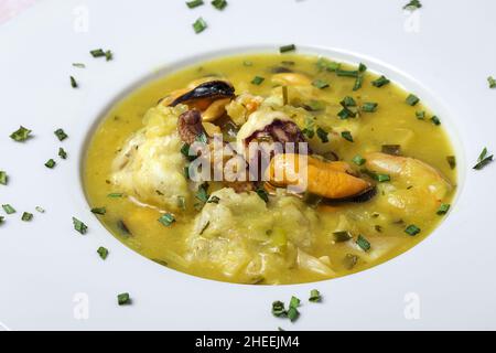 Vue de dessus de plat de gros plan de la cuisine typique du pays basque de lotte avec calmar, crevettes et moules dans la sauce verte garni de persil Banque D'Images