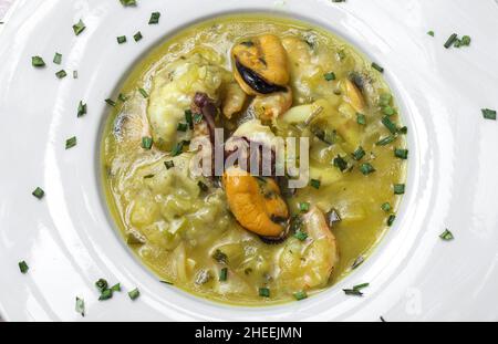 Vue de dessus de plat de gros plan de la cuisine typique du pays basque de lotte avec calmar, crevettes et moules dans la sauce verte garni de persil Banque D'Images