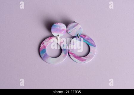 Boucles d'oreilles violettes et bleues sur fond violet. Banque D'Images