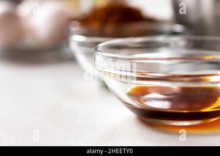 Vue rapprochée de la vanille dans un bol en verre.Autres ingrédients de cuisson flous en arrière-plan.Faible profondeur de champ.Espace de copie en bas à gauche. Banque D'Images