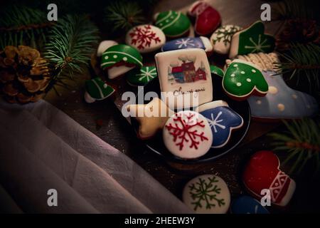 Tableau de bonbons avec biscuits au pain d'épice décorés, branches d'arbre de Noël et cônes de pin sur panneau de bois Banque D'Images