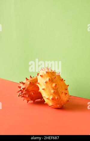 Fruit du dragon, pitahaya.Gros plan sur deux fruits sur un arrière-plan en papier à deux couleurs.Orange vif et vert menthe couleurs vives. Banque D'Images