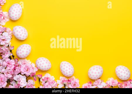 Modèle de Pâques avec œufs Pascal et fleurs de cerisier, carte-cadeau avec espace de copie, fond jaune vif, cadre.Saison de printemps.Tradition chrétienne Banque D'Images