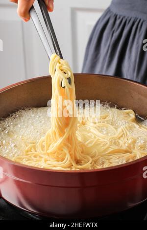 Asiatique femelle cuit à la main nouilles asiatiques (Mie Telur ou bakmi), processus de cuisson dans la cuisine Banque D'Images