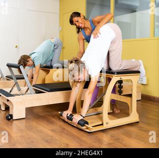 Jeune garçon et fille avec entraîneur pilates dans la salle de gym Banque D'Images