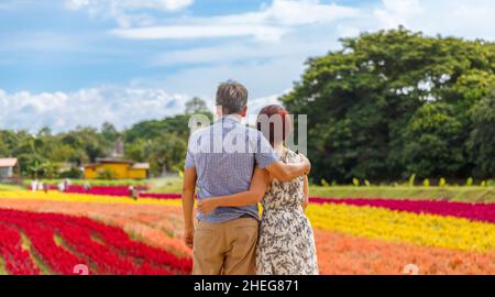 Heureux couple asiatique retraité détendu dans le jardin de fleurs Banque D'Images