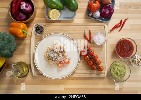 Plat de pâtes italiennes dans une assiette entourée de fruits et légumes frais, sauces maison et épices aromatiques Banque D'Images