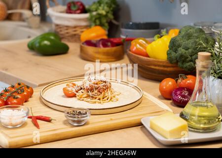 Assiette de pâtes italiennes traditionnelles entourée de légumes frais et d'épices sur une table en bois dans la cuisine Banque D'Images