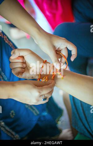 La jeune sœur népalaise noue rakhi au poignet de son frère, une tradition du festival Raksha Bandhan Banque D'Images