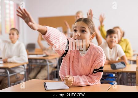 Jeune fille levant la main pendant la leçon à l'école Banque D'Images