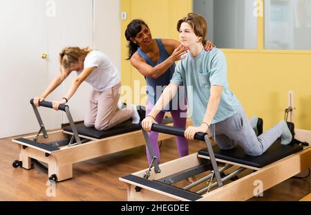 Jeune garçon et fille avec entraîneur pilates dans la salle de gym Banque D'Images