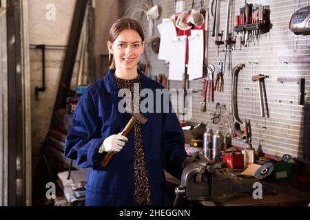 Portrait d'une jeune femme souriante en uniforme qui a un marteau dans sa main Banque D'Images