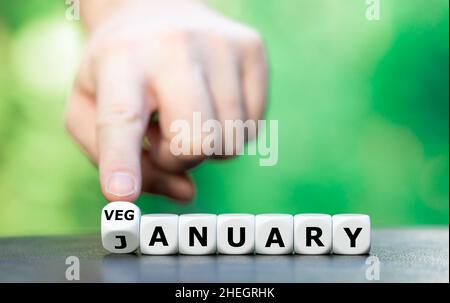 Symbole de la veganiree, un style de vie végétalien pour le mois de janvier.La main tourne les dés et change le mot janvier à Veganiary. Banque D'Images